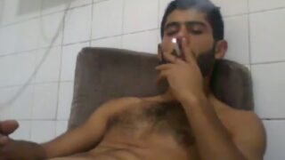 Macho masturbeert terwijl hij een sigaret rookt.